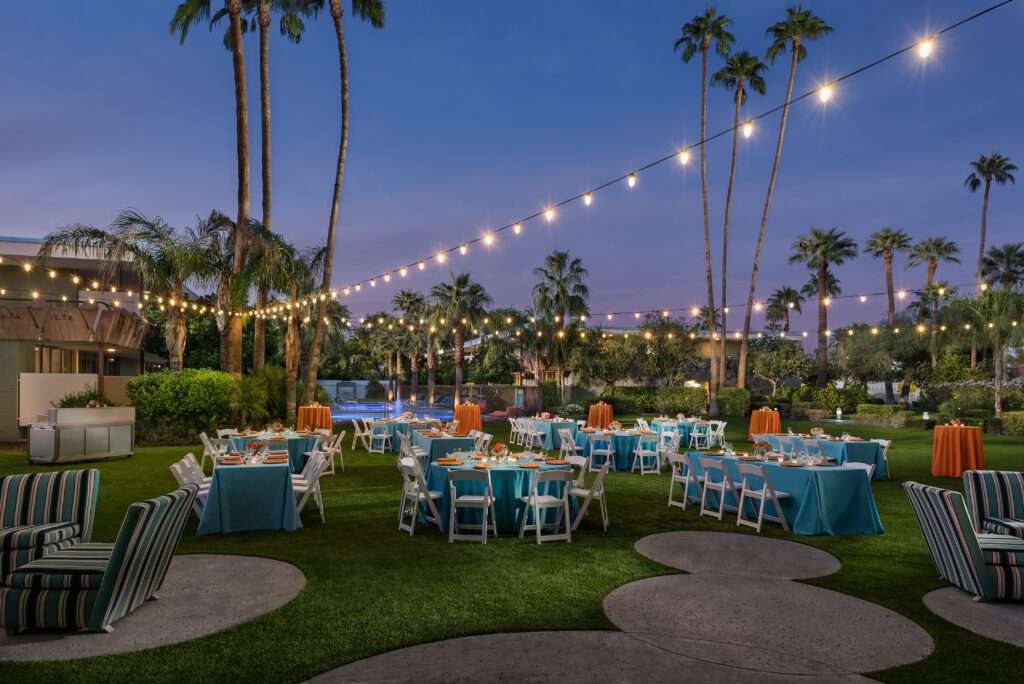 Multiple circular and long tables outside surrounded by chairs.