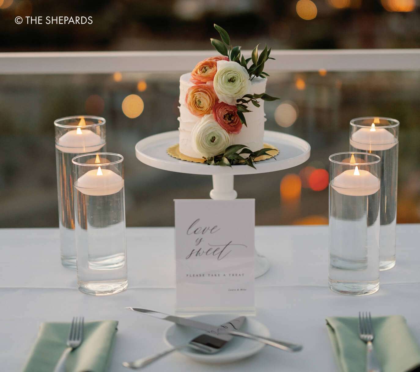 Wedding cake with candles and place card.