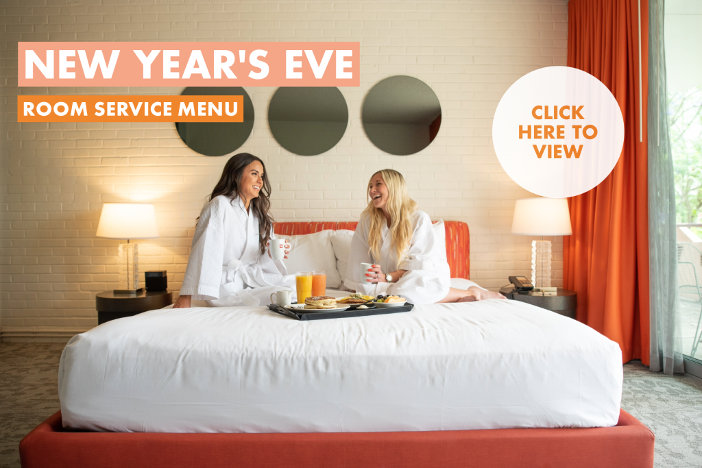 New Year's Eve Room Service Pop Up with two women sitting on the bed in robes with room service breakfast