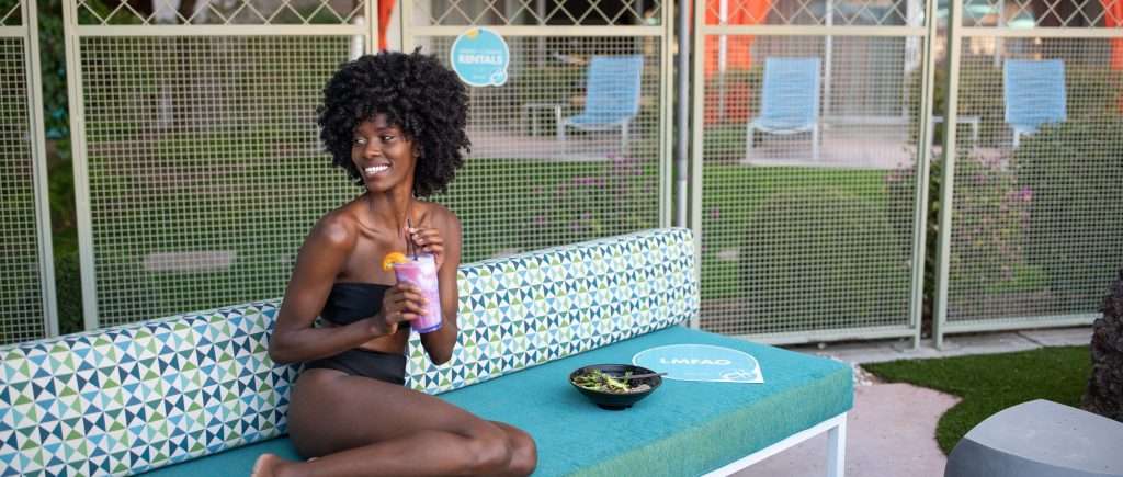 woman on pool lounge chair with cocktail and food