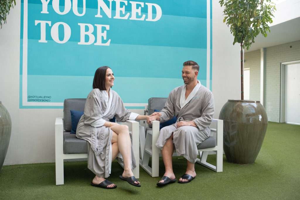 a couple in spa robes in front of the spa mural